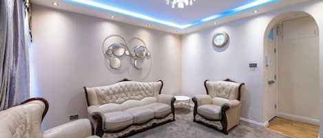 Una sala de estar moderna con un sofá modular, dos sillones, una mesa redonda de centro y arte decorativo en la pared.