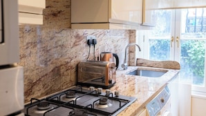Eine Küche mit Gasherd, Toaster, Spüle und einem Fenster mit Blick auf Grünfläche.