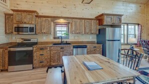 Ein rustikales Blockhaus mit Holzwänden, einem Holzesstisch, einer Küche mit modernen Geräten und einer gemütlichen Sitzecke.