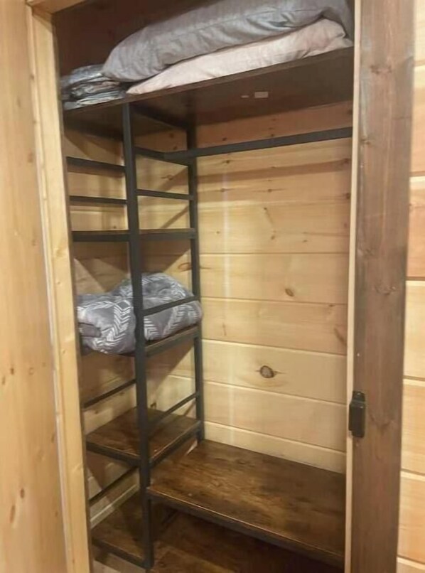 A wooden closet with metal shelves, some items on the top shelf, and a wooden floor. - ~The Laramie~ 2-bedroom, 2 bath Log cabin near Charlotte rustic but comfortable (Cumberland Furnace)