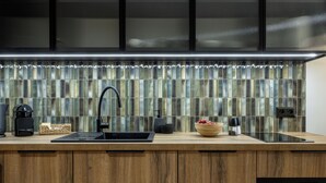A modern kitchen with a wooden countertop, a black faucet, a coffee maker, and a digital clock. -  LILY APART - Rooftop Terrace Apartments by the Shipyard (Gdansk)