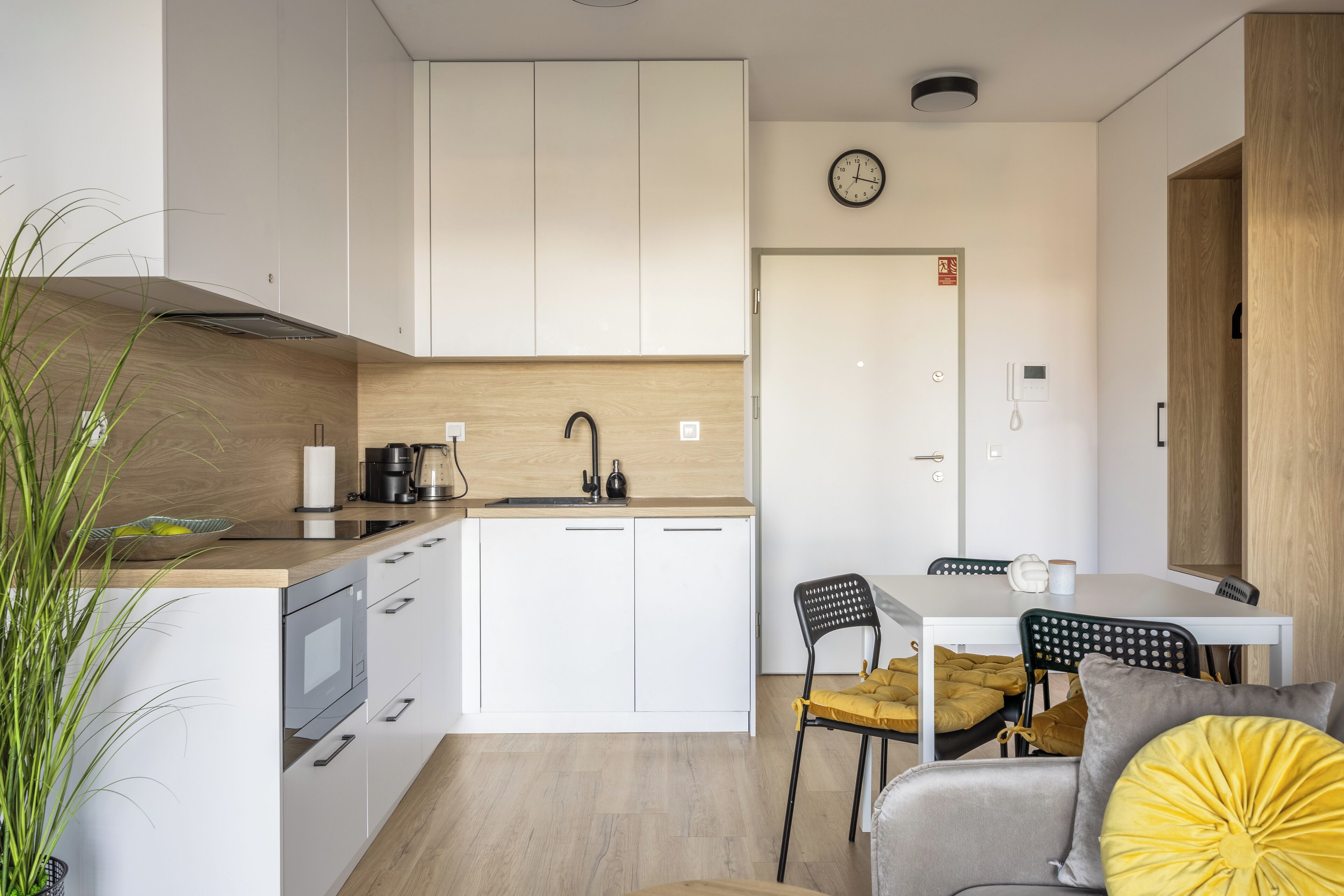 A modern kitchen with white cabinets, a wooden countertop, and a dining area with a table and chairs.