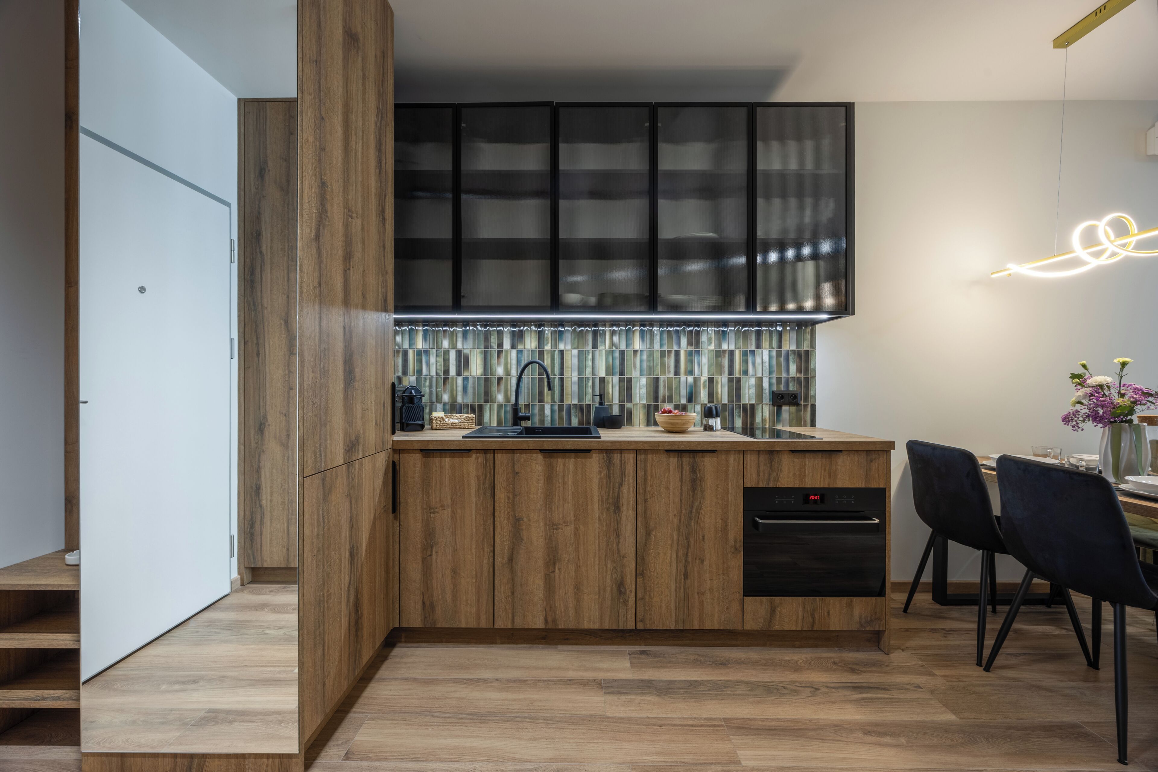 A modern kitchen with wooden cabinetry, a built-in dishwasher, and a dining area with a table and chairs.