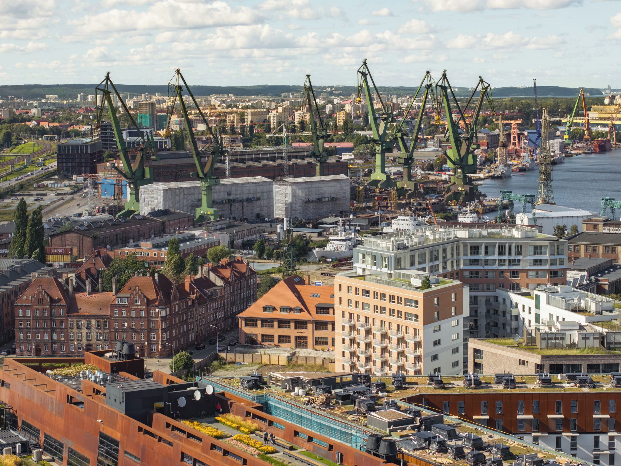 En kuststad med industriella kranar, en hamn och en blandning av historiska och moderna byggnader.