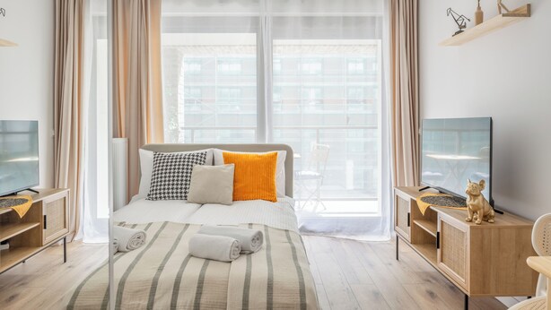 A modern hotel room with a large bed, a television, and a wooden console table. -  LILY APART - Rooftop Terrace Apartments by the Shipyard (Gdansk)