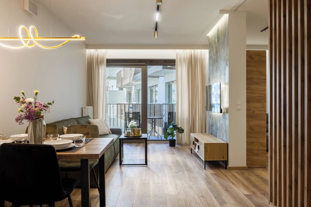 A modern living room with a dining area, a sofa, a coffee table, and a view through a glass door.