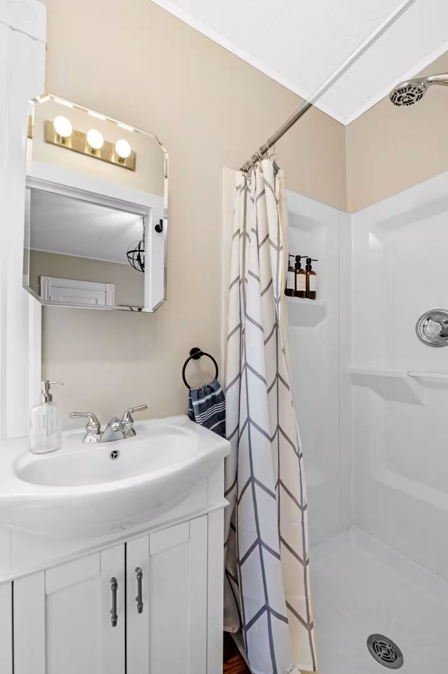 A bathroom with a sink, mirror, and shower curtain.