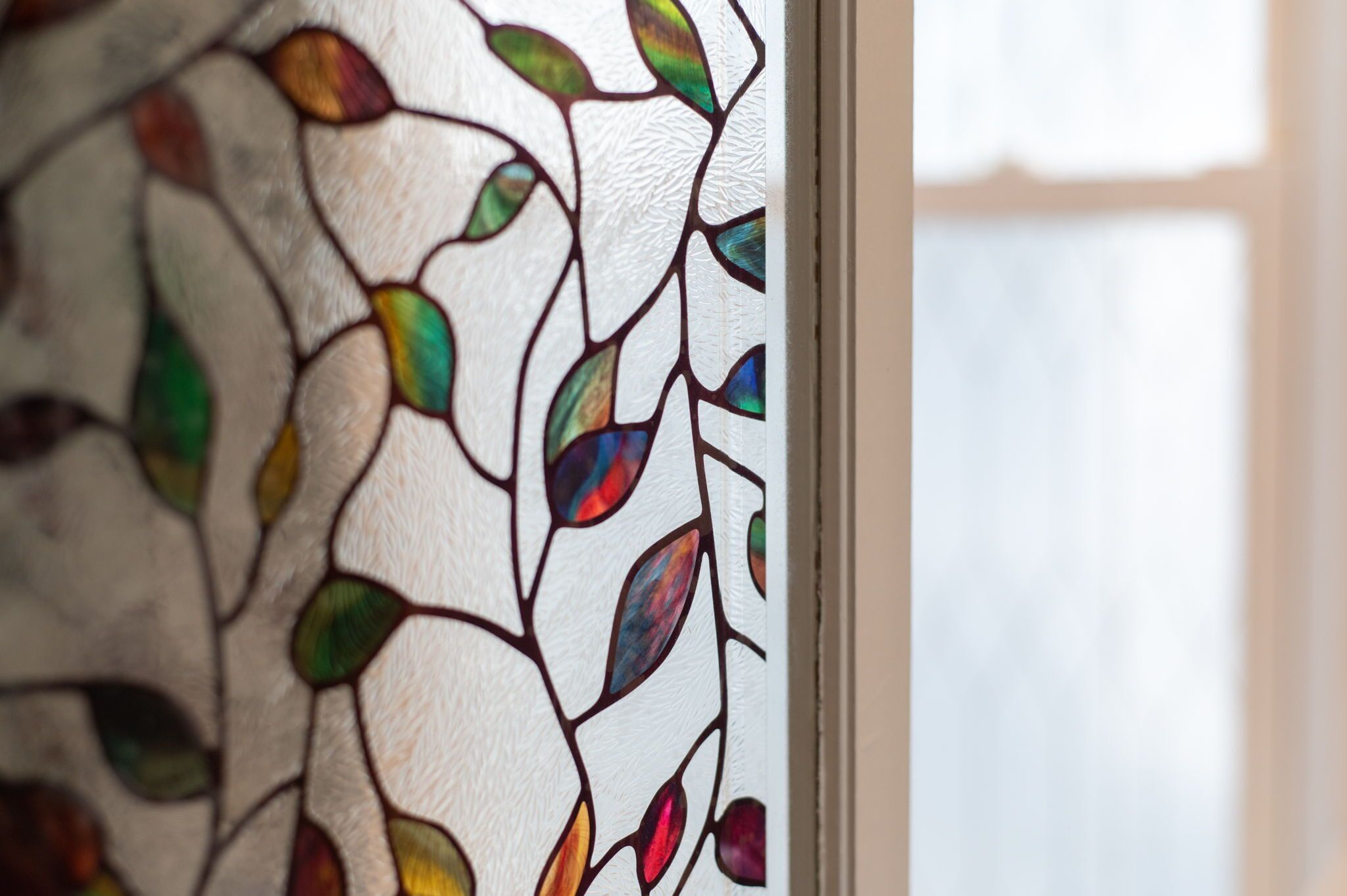 A close-up of a stained glass window with leaf patterns.