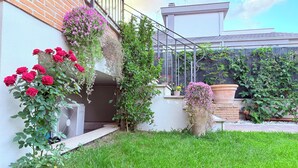 A garden with potted plants and flowers, a brick wall, and a metal railing. - B&B La Fenice Rome - Fiumicino. Close to the center of Rome and the airport. (Lazio)