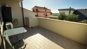 A balcony with a table and chairs, a hose, and an air conditioning unit. - B&B La Fenice Rome - Fiumicino. Close to the center of Rome and the airport. (Lazio)