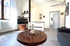 A modern living room with a round wooden coffee table, a flat-screen TV, and a fireplace.