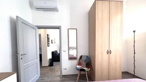 Une chambre d’hôtel avec un lit, une armoire, une chaise et un miroir.