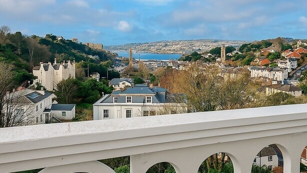 A coastal town with a prominent church tower, a castle on a hill, and a view of the sea.