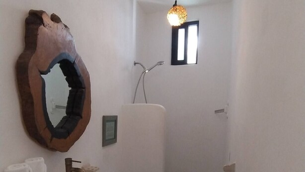 Un baño pequeño con un lavamanos blanco, un espejo y una zona de ducha.