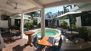Un espacio al aire libre cubierto con piscina, asientos y una escalera que conduce a un nivel superior.
