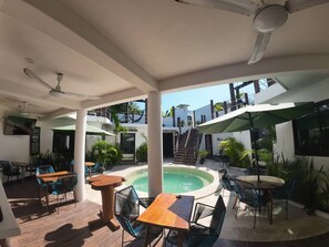 Área externa coberta com piscina, área de estar e escadaria que leva a um andar superior.