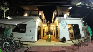 Un hotel de dos plantas con entrada central, un cartel y un espacio para estacionar bicicletas.