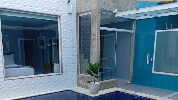 A swimming pool with a blue tiled floor, surrounded by a white and blue building with a modern design. - Pousada Menino do Rio (Buzios)