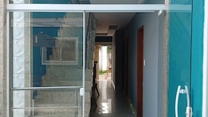 A modern building entrance with a glass door, a concrete exterior, and a blue wall. - Pousada Menino do Rio (Buzios)