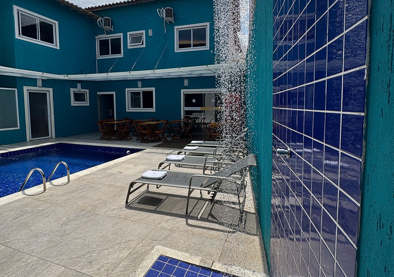 A swimming pool with lounge chairs and a tiled wall.