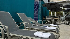 A row of sun loungers with towels, a pool, and umbrellas. - Pousada Menino do Rio (Buzios)