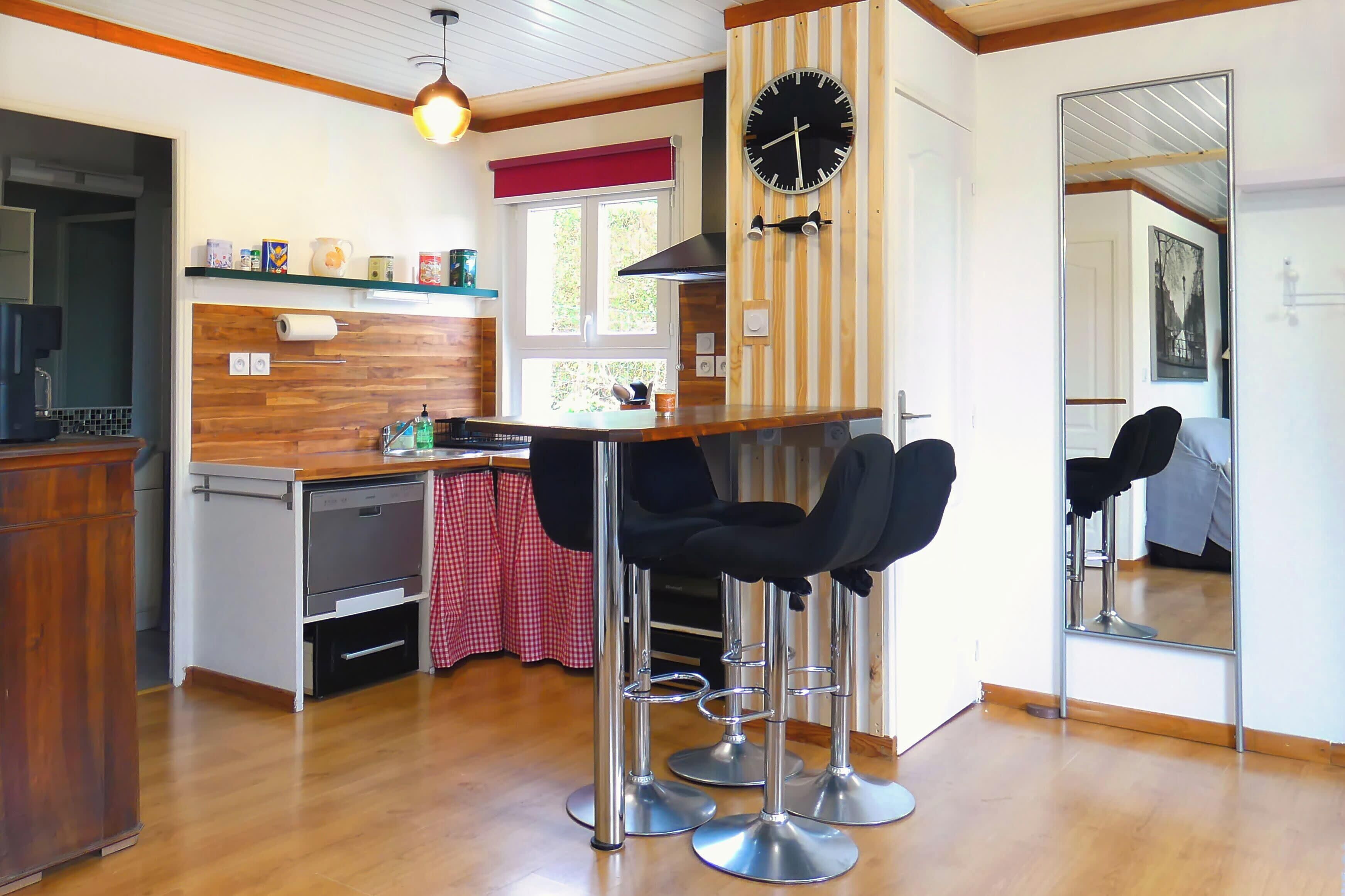 A kitchen with wooden cabinets, a stainless steel sink, and a bar area with stools.