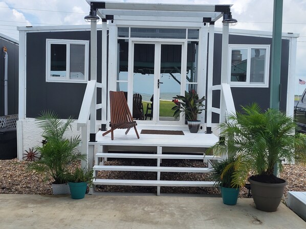 A modern house with a porch, a wooden chair, and potted plants.