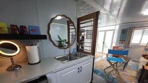 Una cocina moderna con un lavamanos empotrado, un espejo redondo con luz y un armario blanco.