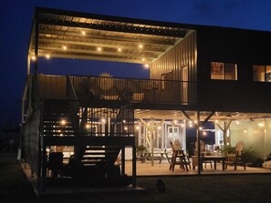 A two-story building with a covered outdoor area featuring tables and chairs, and a staircase leading to an upper level.