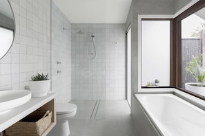 Bathroom features a large bathtub, wall-mounted mirror, and a shower area with a glass door.