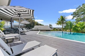 Relax by the serene pool surrounded by lush greenery and palm trees.