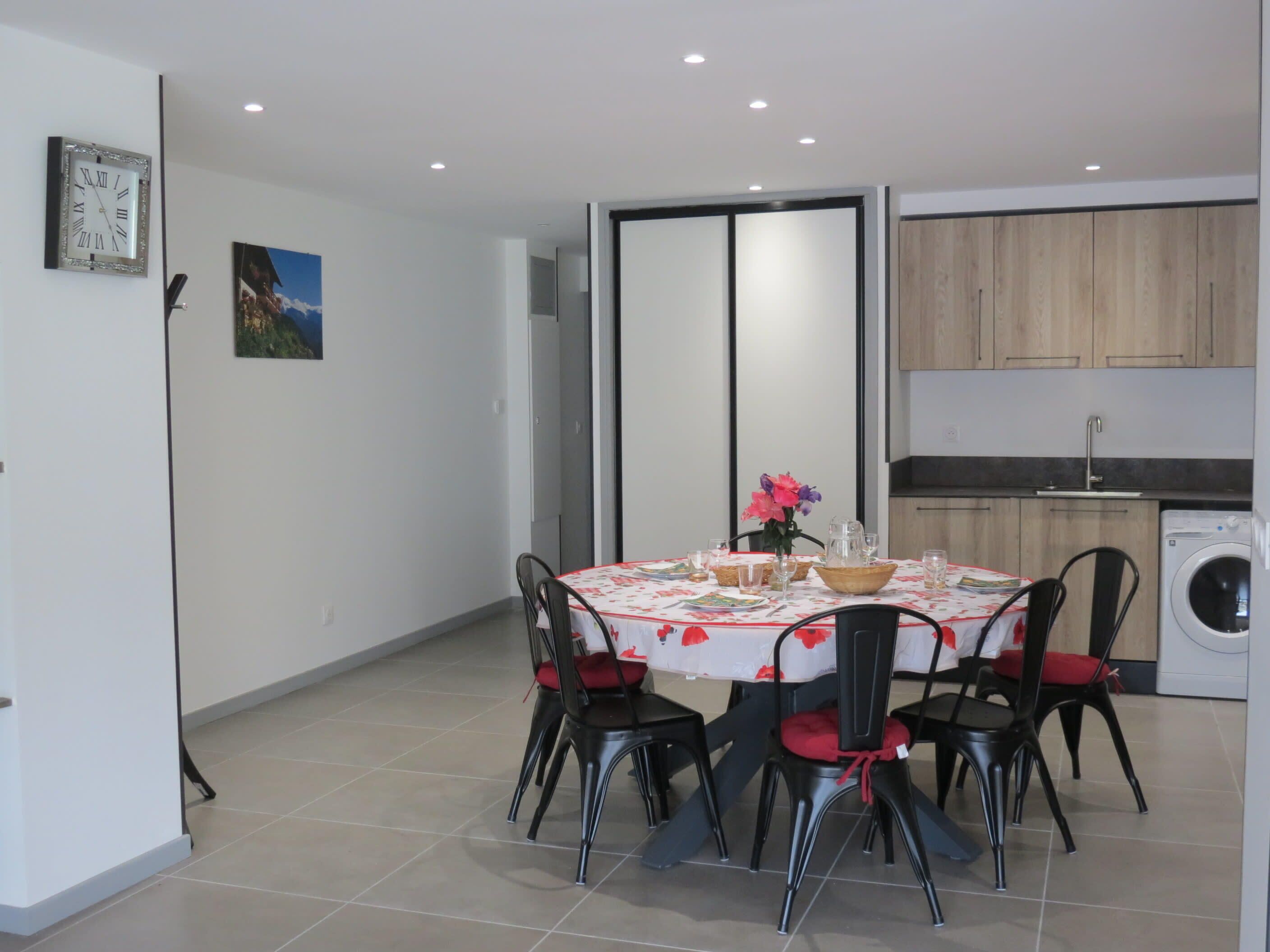 Un coin repas avec une table ronde, des chaises et un lave-linge en arrière-plan.