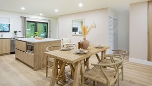 Eine moderne Küche mit Holzschränken, einer zentralen Kochinsel und einem Essbereich mit Holztisch und Stühlen.