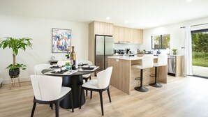 A modern kitchen with a central island, a dining area with a round table, and a view of the outdoors. - ` The Black Vanilla ` Luxe Retreat Sauna, Cold Plunge & Pure Relaxation (Naples)