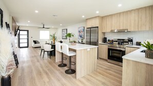 A modern kitchen with a central island, stainless steel appliances, and light wood cabinetry. - ` The Black Vanilla ` Luxe Retreat Sauna, Cold Plunge & Pure Relaxation (Naples)
