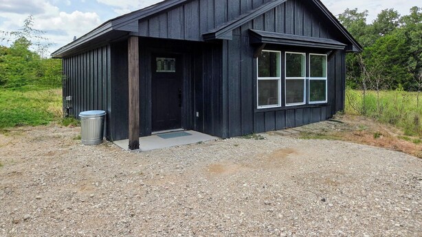 A black wooden building with a sloped roof and a large window. - Wonderful Pondview Cottage in College Station (College Station)