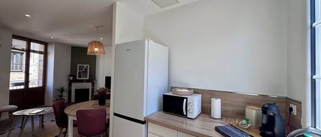 Una cocina moderna equipada con refrigerador, microondas y cafetera. Hay un comedor con mesa y sillas.