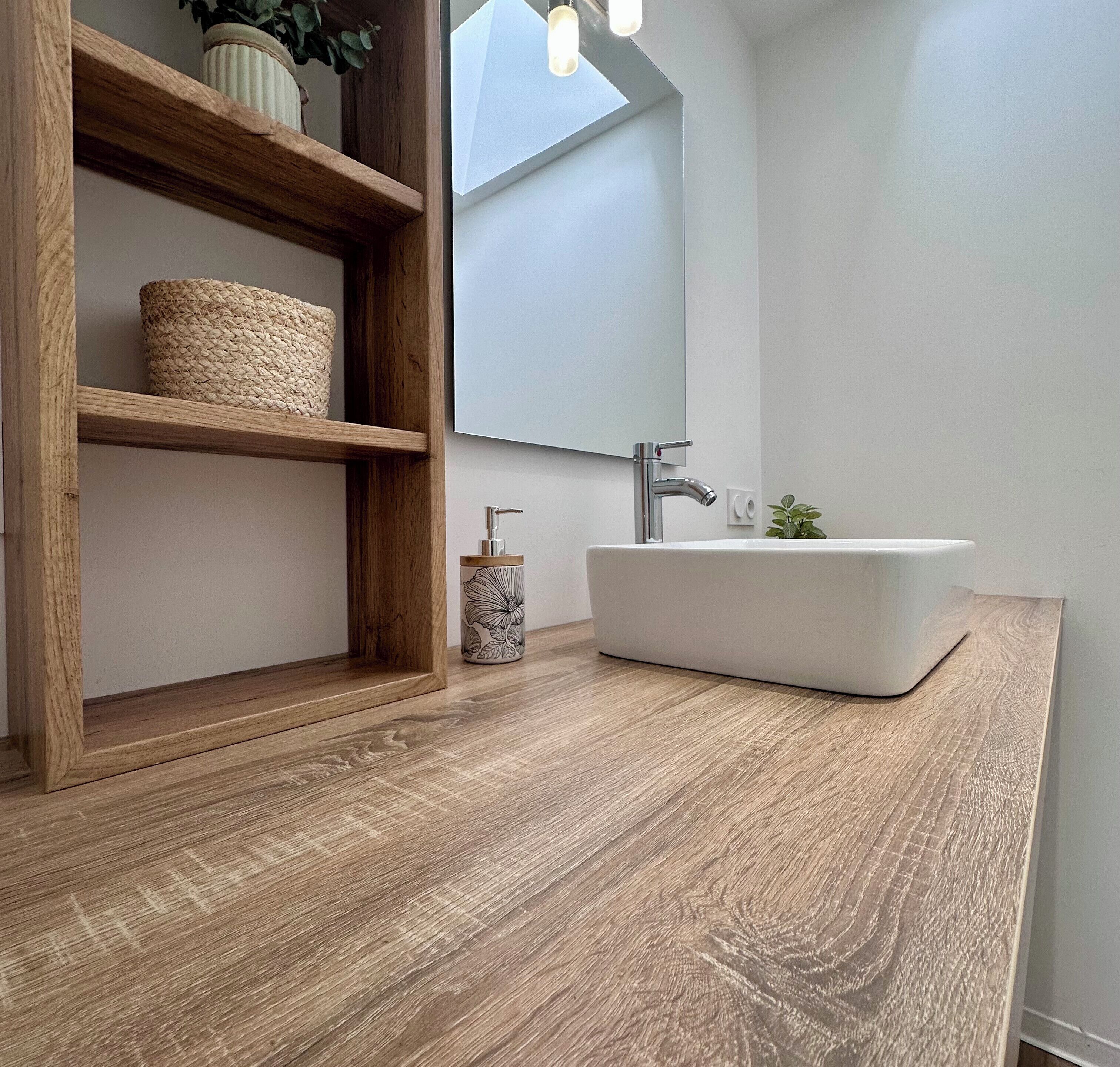 Een badkamer met een houten wastafelmeubel, een witte wasbak en een spiegel.