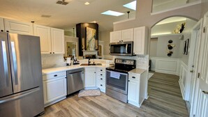 Una cocina moderna con armarios blancos, electrodomésticos de acero inoxidable y un tragaluz.