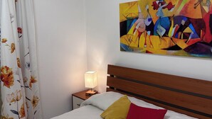 A hotel room with a bed, a nightstand, a lamp, a painting, and an air conditioning unit. - VACATION HOME OF THE FISHERMAN (Tonnarella)