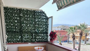 A balcony with a wooden table and bench, a decorative wall, and a view of the street. - VACATION HOME OF THE FISHERMAN (Tonnarella)