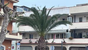 A residential building with balconies, a palm tree, and parked cars. - VACATION HOME OF THE FISHERMAN (Tonnarella)