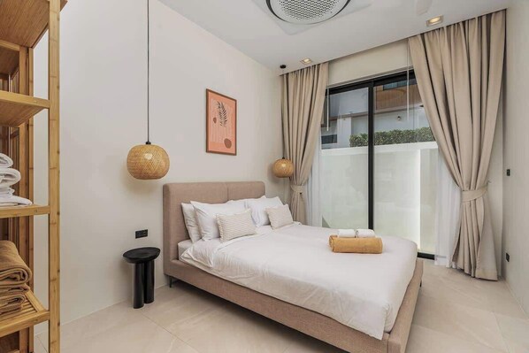 Une chambre à coucher moderne avec un grand lit, une petite table de chevet, une lampe suspendue et une fenêtre avec des rideaux.