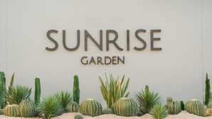 A sign for Sunrise Garden with various cacti and succulents in front.