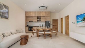 A modern living room with a sofa, coffee table, and dining area with chairs.