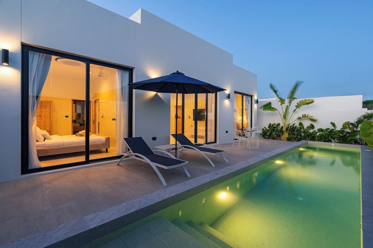 Une chambre d’hôtel moderne avec une porte en verre, une piscine et des chaises longues.