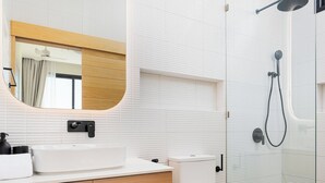 A modern bathroom with a wooden vanity, a large mirror, a toilet, and a glass-enclosed shower area. - Staylar Pool Villa - Bangtao, Phuket C1 (Phuket, Bangtao)