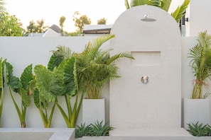Une entrée moderne avec un mur blanc et une arche circulaire, le tout agrémenté de différentes plantes.
