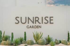 Een bordje voor Sunrise Garden met diverse vetplanten en vetplantsoorten erbij.