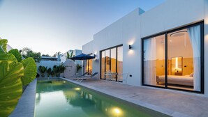 A modern hotel with a swimming pool, sun loungers, and a well-lit bedroom visible through large sliding doors. - Staylar Pool Villa - Bangtao, Phuket C1 (Phuket, Bangtao)